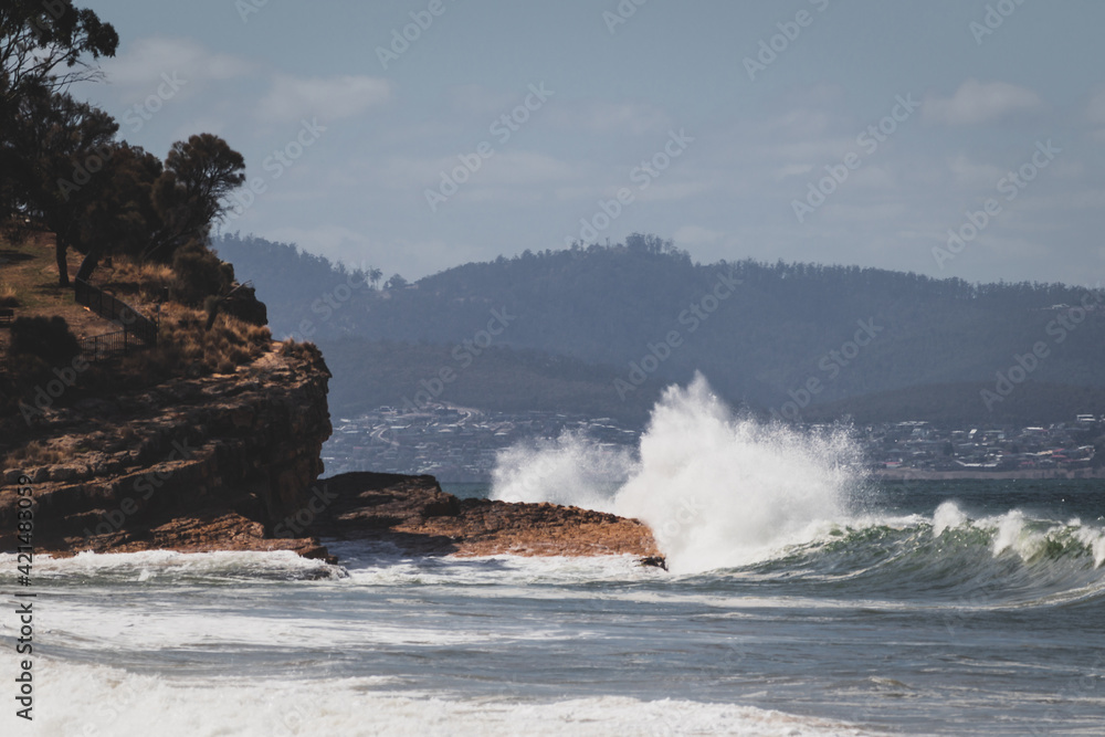 big waves crashing against rocky shoreline in Tasmania, Australia