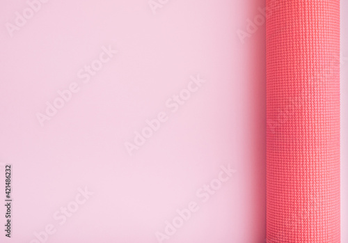 Monochrome fitness theme with pink yoga exercise mat on light background. Flat lay with copy space.