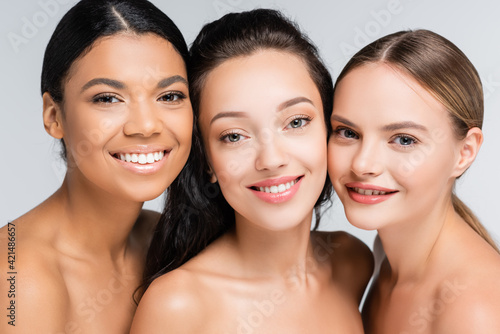 cheerful multiethnic women with bare shoulders isolated on grey