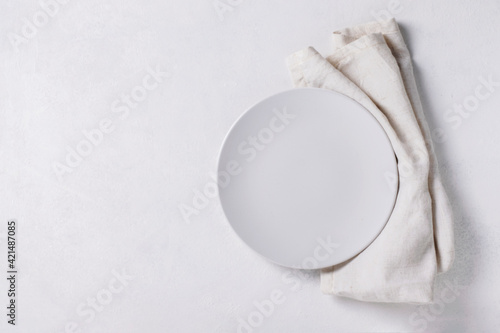 White empty plate with napkin on white background with copy space.