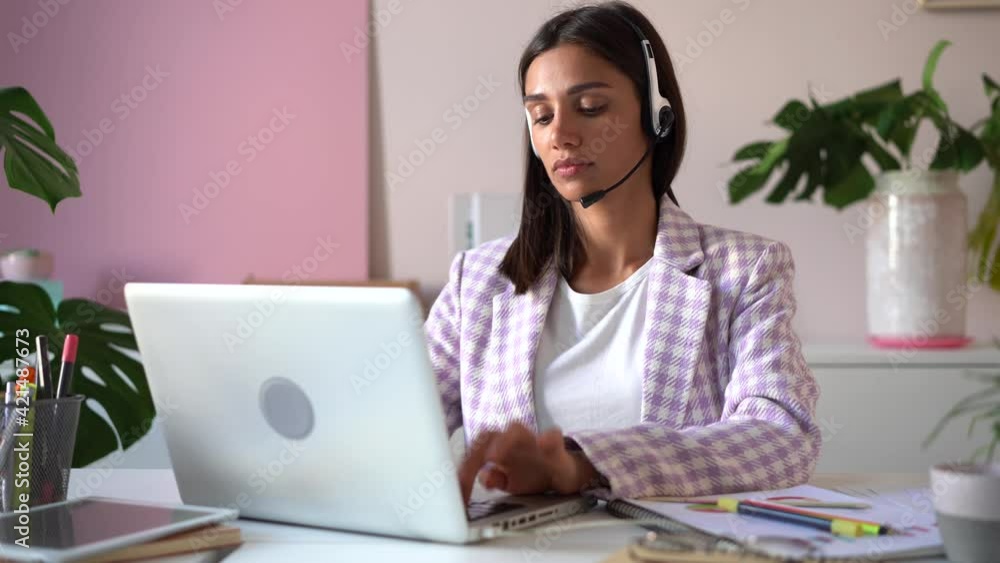 Indian mixed-race businesswoman working on laptop computer in office. Female manager typing on laptop keyboard indoors