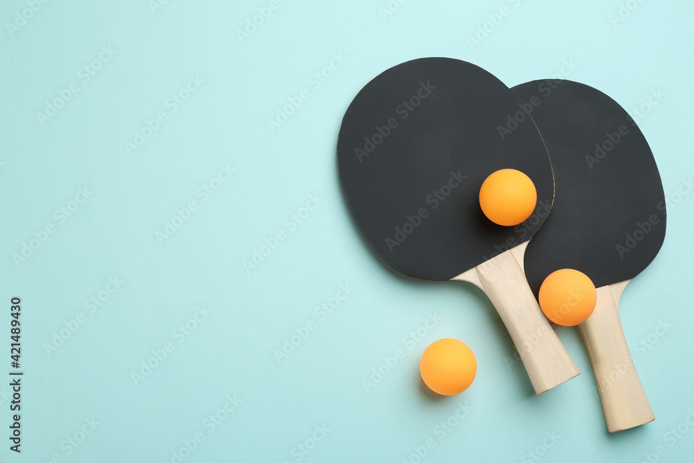 Ping pong rackets and balls on turquoise background, flat lay. Space for text Ping pong rackets and balls on turquoise background, flat lay. Space for text