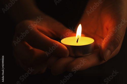 Woman with burning candle in darkness, closeup. Memory day