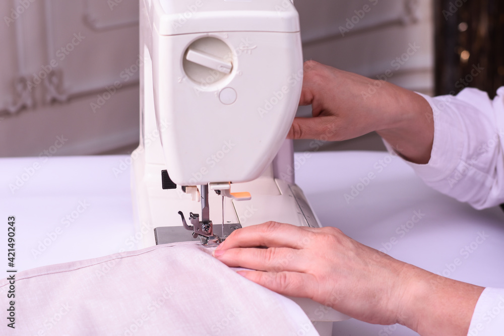 A seamstress working on a sewing machine. Women's hands in the process of sewing. side view.