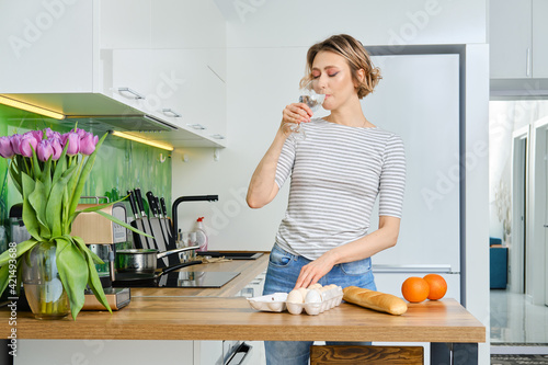 Beautiful young woman drinks water before making breakfast