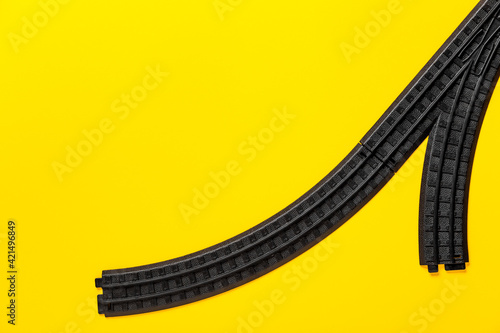 Part of the children railway. Banner with element of child toy and copy space on yellow background. Part rails constructor. Two forking ways. Game roads. Nobody. Career concept. Empty place for text photo