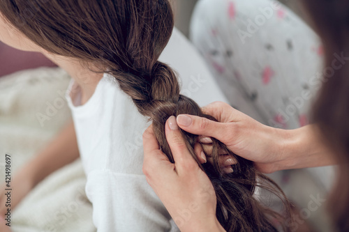 Photography Female hands braiding long dark hair in braid