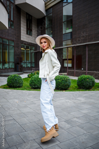 Beautiful young woman freelancer in beautiful stylish clothes walking outdoors on the background of an office building