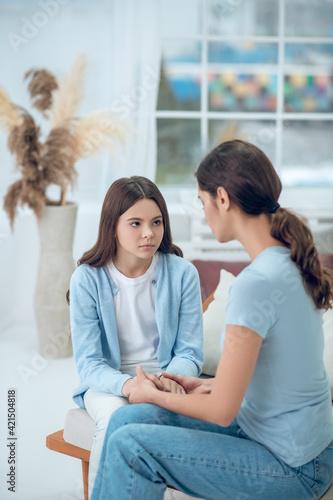 Upset daughter looking at mom sitting next to her