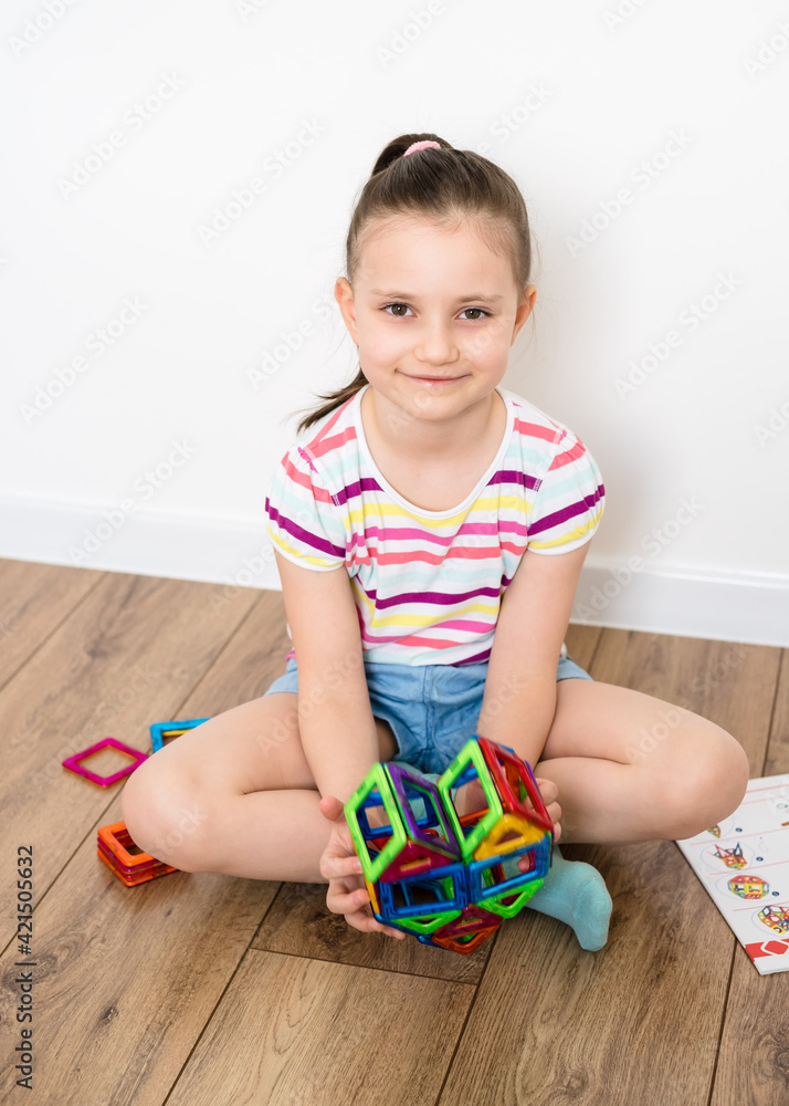 Kid plays with a magnetic constructor toy. A little child girl is playing with colorful blocks. Heart from a magnetic constructor. Kid plays with a magnetic constructor toy. A little child girl is playing with colorful blocks. Heart from a magnetic constructor.