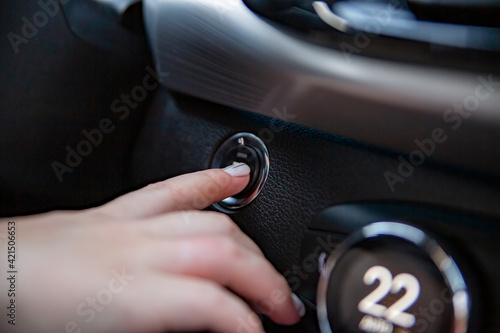 hand finger presses the start stop button in a modern car. close-up. no face. selective focus