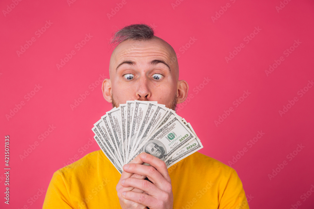 European man on pink red background with fan on 100 dollars shocked excited amazed isolated space European man on pink red background with fan on 100 dollars shocked excited amazed isolated space