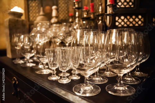 many different empty glass goblets on a dark table in a restaurant. defocus, soft focus, blur