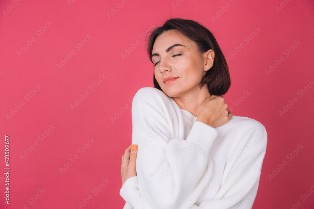 Beautiful woman in casual white sweater on pink red background love concept, holding hands crossed hugging herself isolated copy space closed eyes Beautiful woman in casual white sweater on pink red background love concept, holding hands crossed hugging herself isolated copy space closed eyes