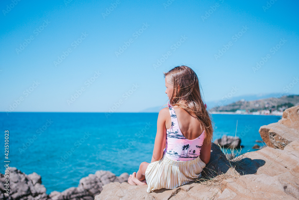 Little girl outdoor on edge of cliff seashore