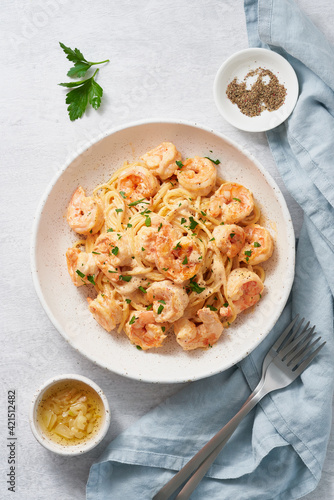 Pasta spaghetti with grilled shrimps bechamel sauce. Spaghetti with seafood rich cream. Cooking mediterranean food with savory prawns, top view, blue table, italian cuisine, vertical
