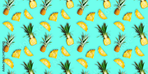 Seamless pattern of ripe pineapples isolated on green background. Top view. Tropical fruit summer exotic concept