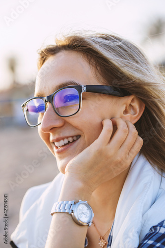 Young blond woman at the beach on a cold day. Portrait of Cheerful Woman with glasses. Vertical photo