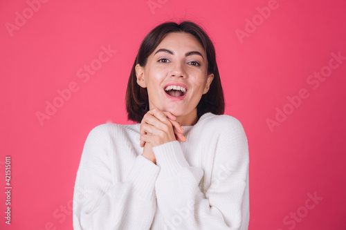 Woman in white casual sweater on red pink background copy space cheerful excited amazed look to camera