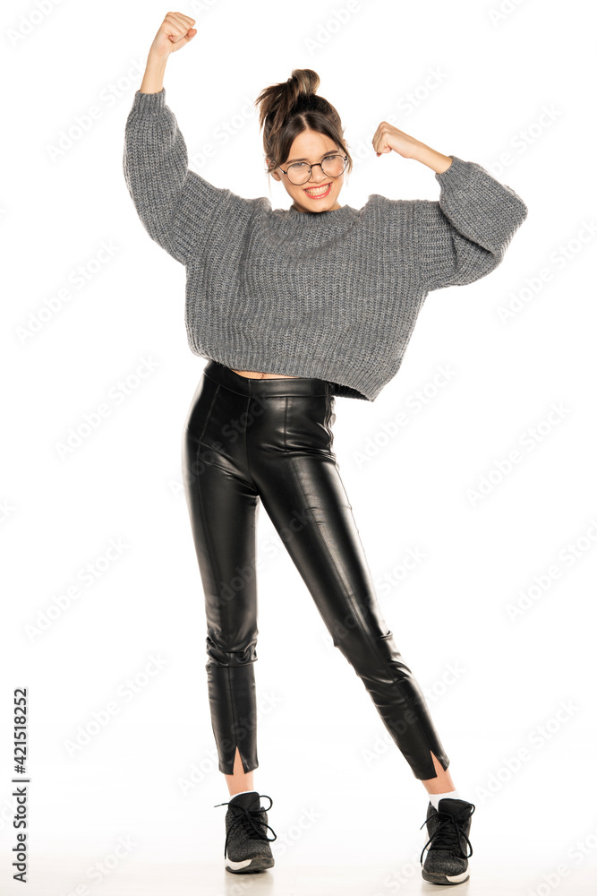 a young beautiful happy teen in leather pants and a sweater in winning gesture a young beautiful happy teen in leather pants and a sweater in winning gesture