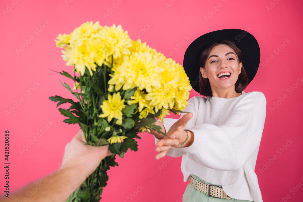 Stylish woman in hat and casual white sweater on pink red background gets large bouquet of yellow flowers, spring mood, isolated space amazed excited surprised Stylish woman in hat and casual white sweater on pink red background gets large bouquet of yellow flowers, spring mood, isolated space amazed excited surprised