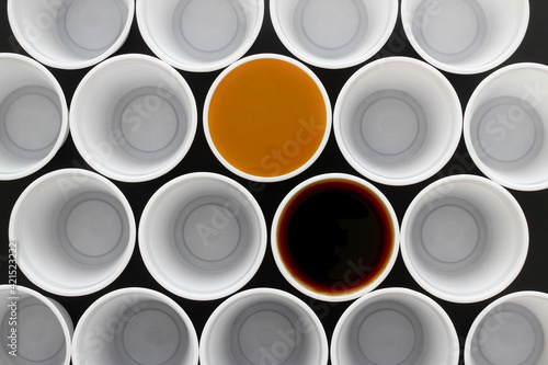 Two coffee in many white plastic disposal cups, one with milk, one black coffee, view from above