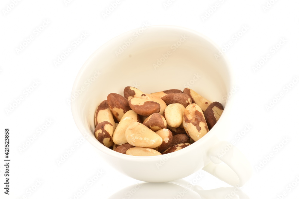 Several ripe organic Brazil nuts in a ceramic cup, close-up. The background is white.