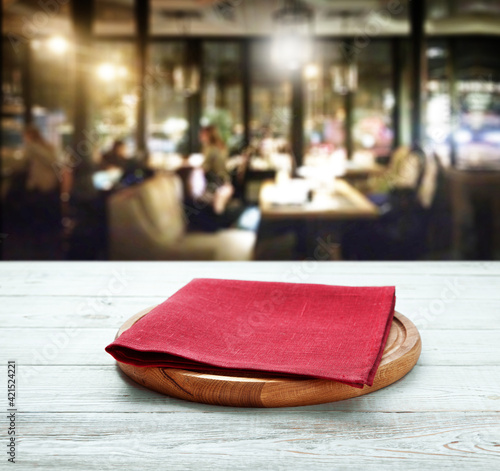 Napkin and pizza board on wooden desk top view mock up. Pizzeria interior. Selective focus.