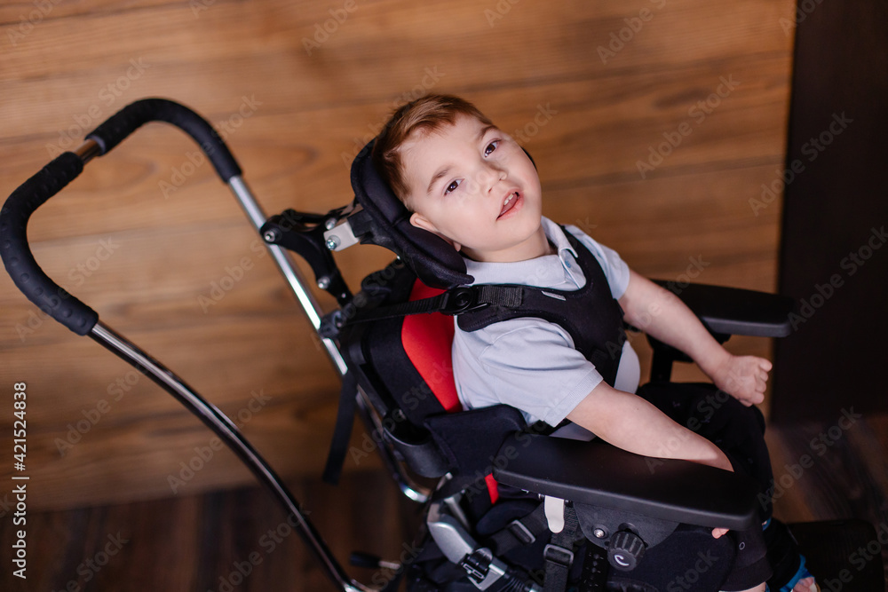 beautiful boy child in a special wheelchair. Toddler with cerebral palsy. Rehabilitation process at home indoor. Lifestyle moments. beautiful boy child in a special wheelchair. Toddler with cerebral palsy. Rehabilitation process at home indoor. Lifestyle moments.