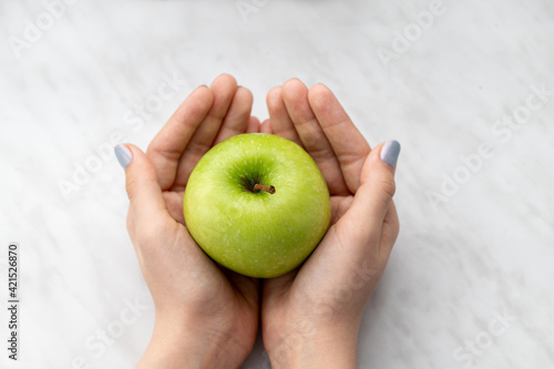 A green apple in the hands of a child.