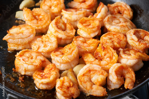 Keto meal fried shrimp for ketogenic diet, preparing sauce for pasta, seafood prawn sizzling in teflon frying pan, hot pan-fried paleo food with crispy crust of food rich in cholesterol