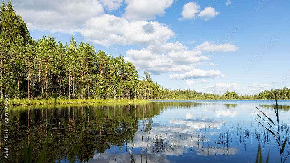 Beautiful summer landscape. Clouds in the blue sky. Reflection of clouds on water surface. Finland. Pure nature, ecology, environmental conservation, travel destinations.