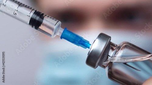 Doctor in medical mask holds in hands syringe and vaccine bottle at the hospital
