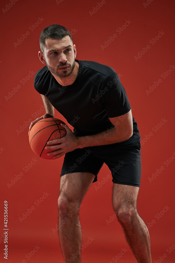 Focused seriously sportsman in black sportswear training isolated on red background Focused seriously sportsman in black sportswear training isolated on red background