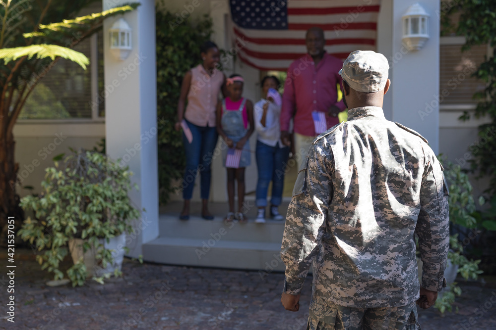 African american soldier father in front of wife, children and father greeting him outside house