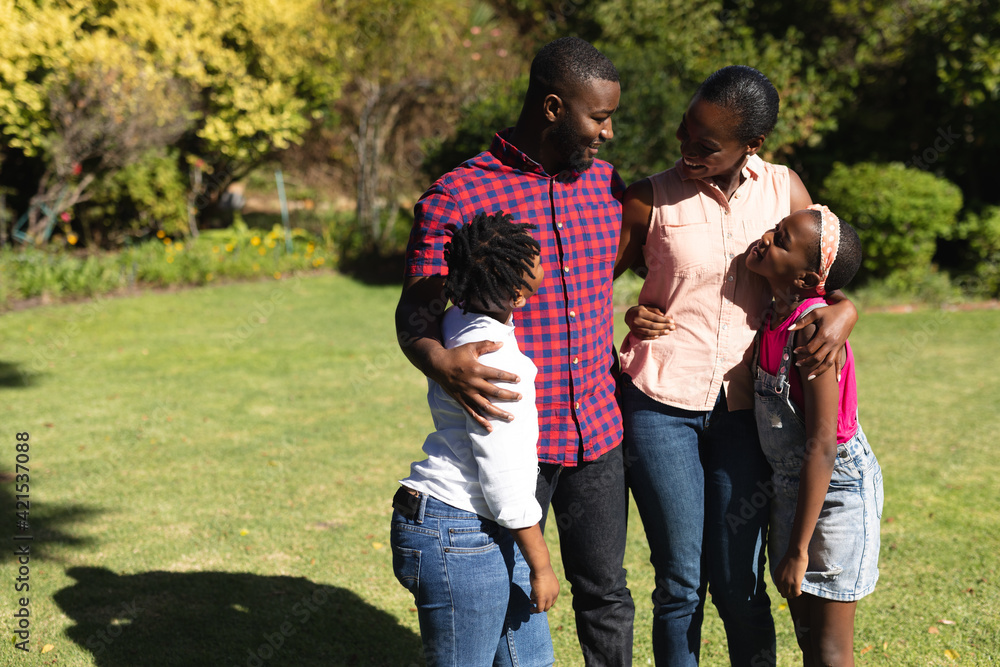 Smiling african american parents with daughter and son standing embracing outdoors