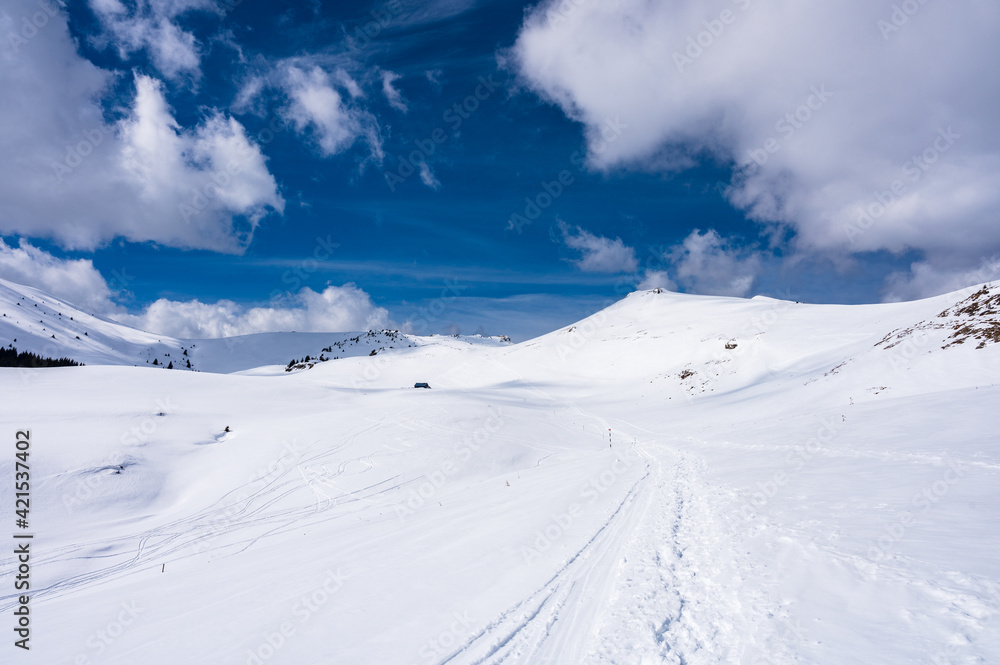 Sunny day on a snowy hiking trail in Romanian Bucegi mountains in winter