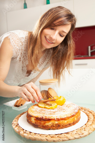 Young blonde caucasian woman smiling and preparing a lemon cheesecake in a kitchen