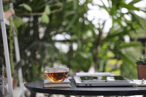 Tea cup glass and tablet on black wooden table at outdoor
