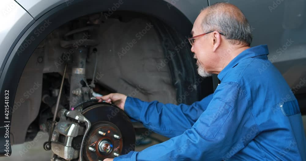Asian man mechanic changing car wheel at Car maintenance and auto service garage. Young male worker people Asian man mechanic changing car wheel at Car maintenance and auto service garage. Young male worker people
