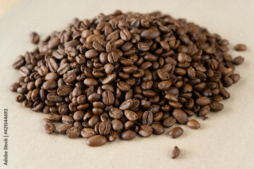a handful of roasted coffee beans on a beige background