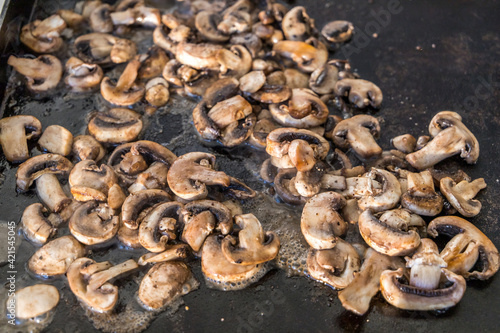 Photography sauteed mushroom slices on an outdoor griddle propane grill in the summer