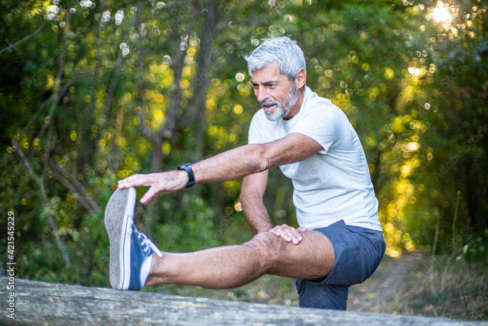 © PhotoAlto - Mature man stretching his leg in forest © PhotoAlto - Mature man stretching his leg in forest