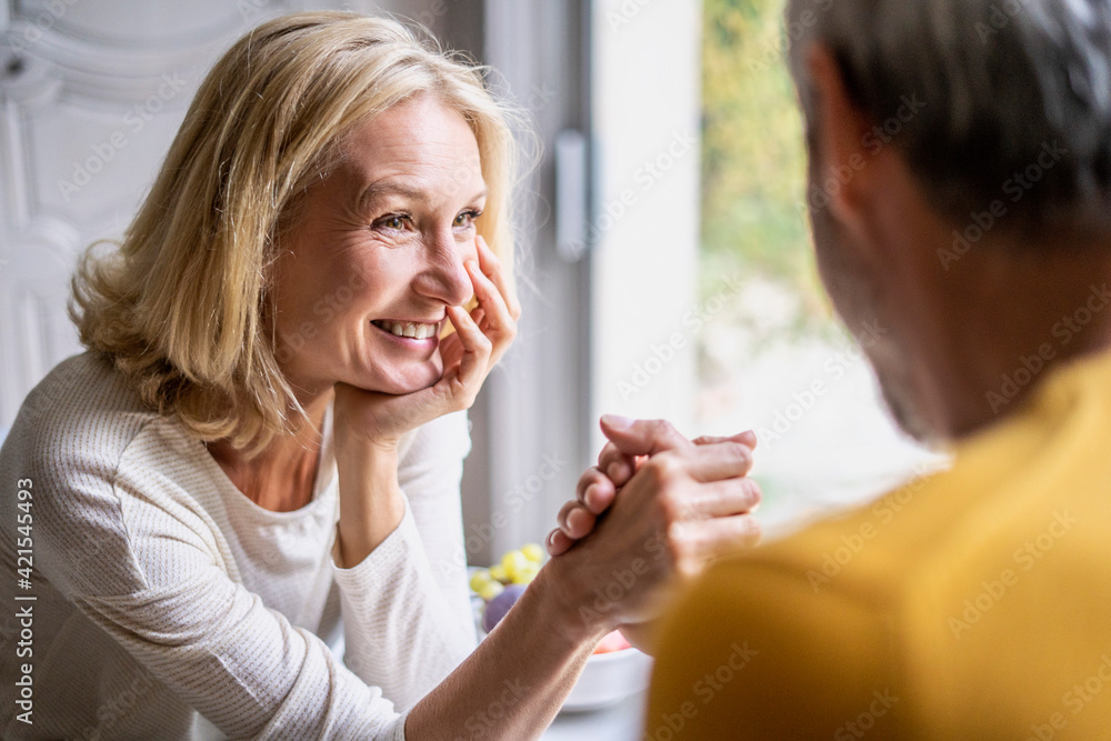 Smiling mature couple arm wrestling at home