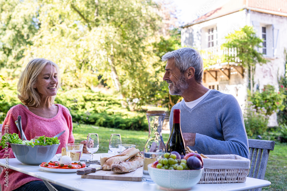 Smiling mature couple enjoying meal while sitting at table Smiling mature couple enjoying meal while sitting at table