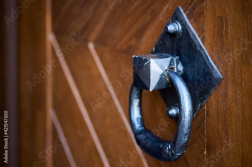 Door handle knocker selective focus on brown old wooden church entrance door side view with copyspace.