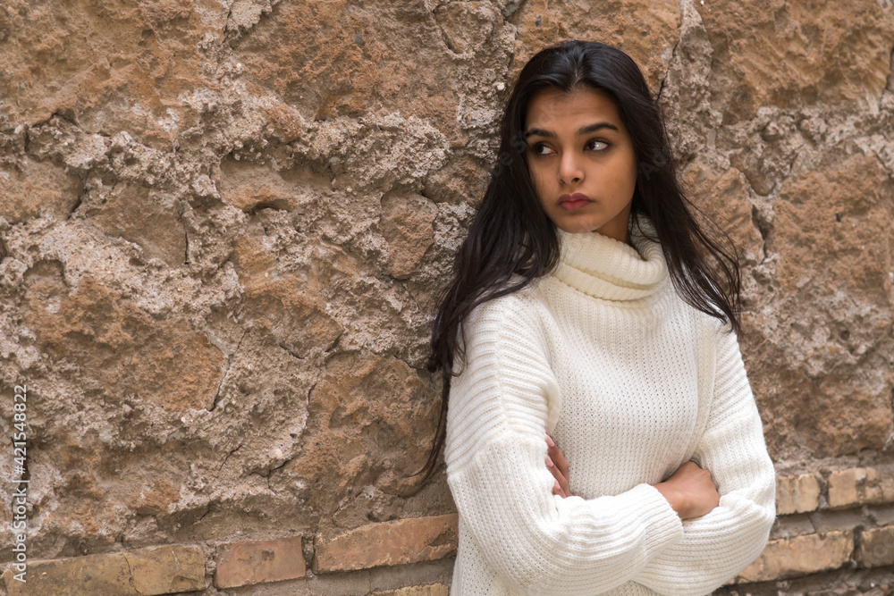 Portrait of a young romantic brunette woman leaning against a brick wall with crossed arms. Outdoors Portrait of a young romantic brunette woman leaning against a brick wall with crossed arms. Outdoors