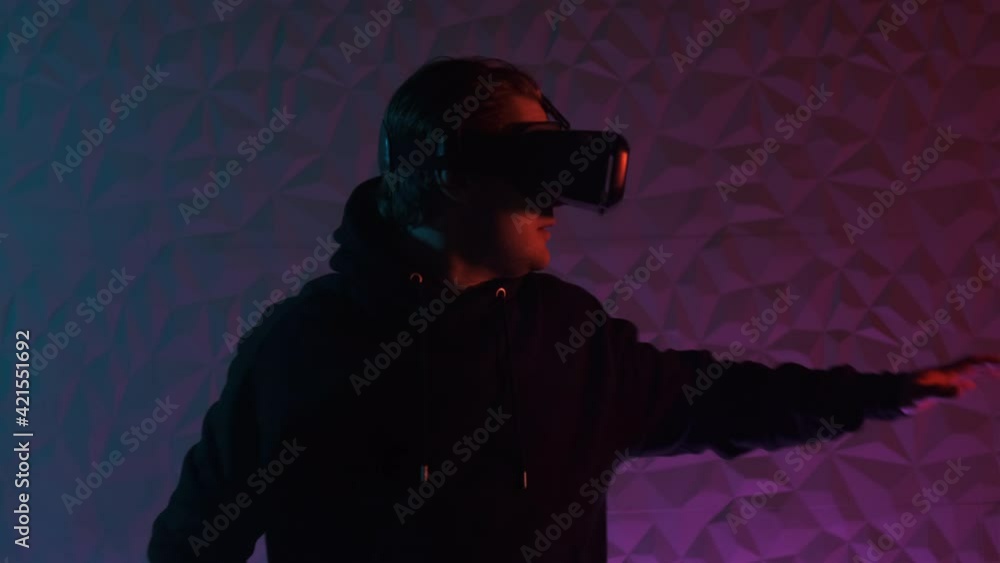 Close up view man in black hoodie and VR helmet on his head move left and right and puts his hands in front of him. A lot of smoke around. Gamer play virtual reality games. Close up view man in black hoodie and VR helmet on his head move left and right and puts his hands in front of him. A lot of smoke around. Gamer play virtual reality games.