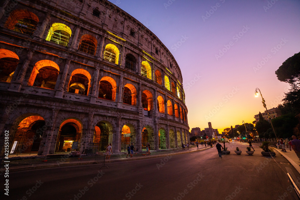 Low angle view of tourists walking on street outside Colosseum at dusk, Rome