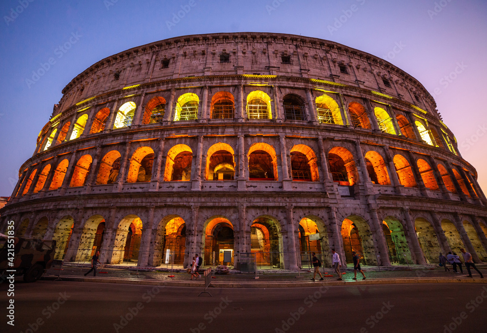 Low angle view of tourists walking on street outside Colosseum at dusk, Rome